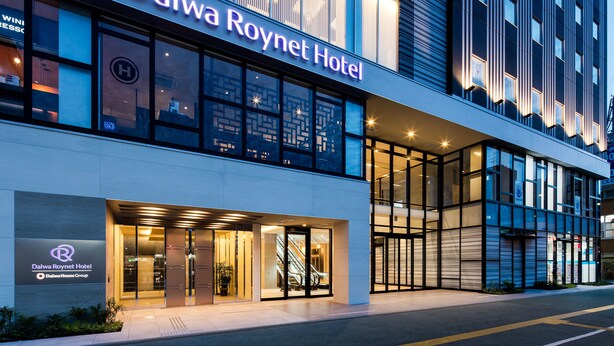 Exterior del hotel Daiwa Roynet, con fachada moderna, ventanas amplias y una entrada visible con puertas de vidrio.