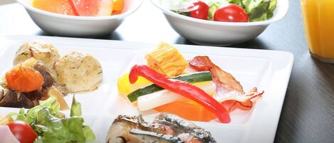 A table with various dishes including a salad, a fruit bowl, and a plate with vegetables and meat.