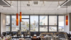 Zona de bufé con diversas opciones de comida y vistas a la ciudad a través de amplias ventanas.