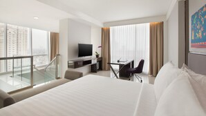 Habitación de hotel moderna con una cama grande, un escritorio, un televisor y un balcón con vistas a la ciudad.