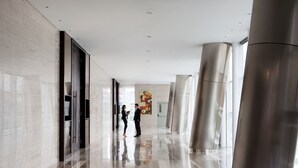 Un pasillo moderno de hotel con suelos reflectantes, amplias columnas metálicas y un diseño minimalista.