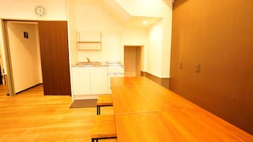 Habitación de hotel con una mesa de comedor de madera, kitchenette y piso de madera.