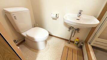 A small bathroom with a toilet, sink, and wooden floor.