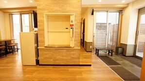 Un hall de hotel con una recepción, un área de descanso pequeña y una escalera que lleva a los pisos superiores.
