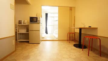 A compact kitchen with a refrigerator, microwave, and a small dining table with stools.