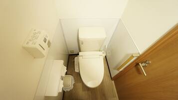 A compact bathroom with a white toilet, a small sink, and a wooden door.