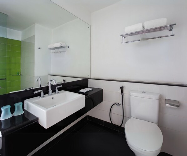 Un baño moderno con un lavamanos blanco, encimera negra y un inodoro.