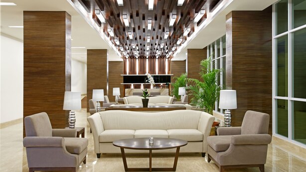 Um lobby moderno com um sofá, poltronas e uma mesa de centro.