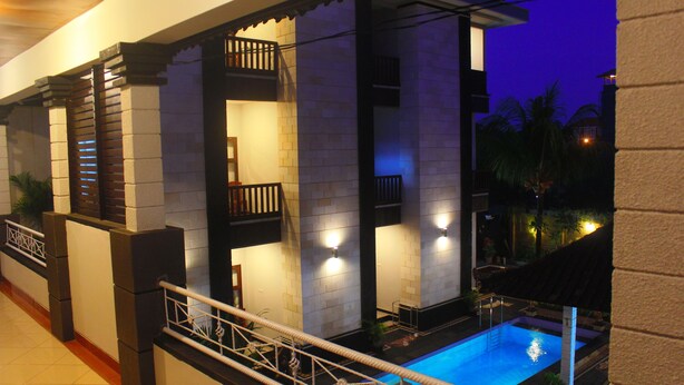 A modern building with a pool, balconies, and a railing. - New Asta Graha Homestay (Kedonganan)