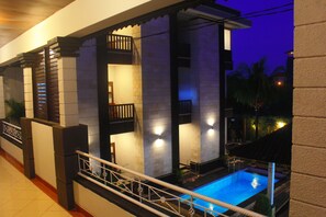 A modern building with a pool, balconies, and a railing. - New Asta Graha Homestay (Kedonganan)