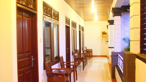 A hallway with wooden doors and a row of chairs. - New Asta Graha Homestay (Kedonganan)