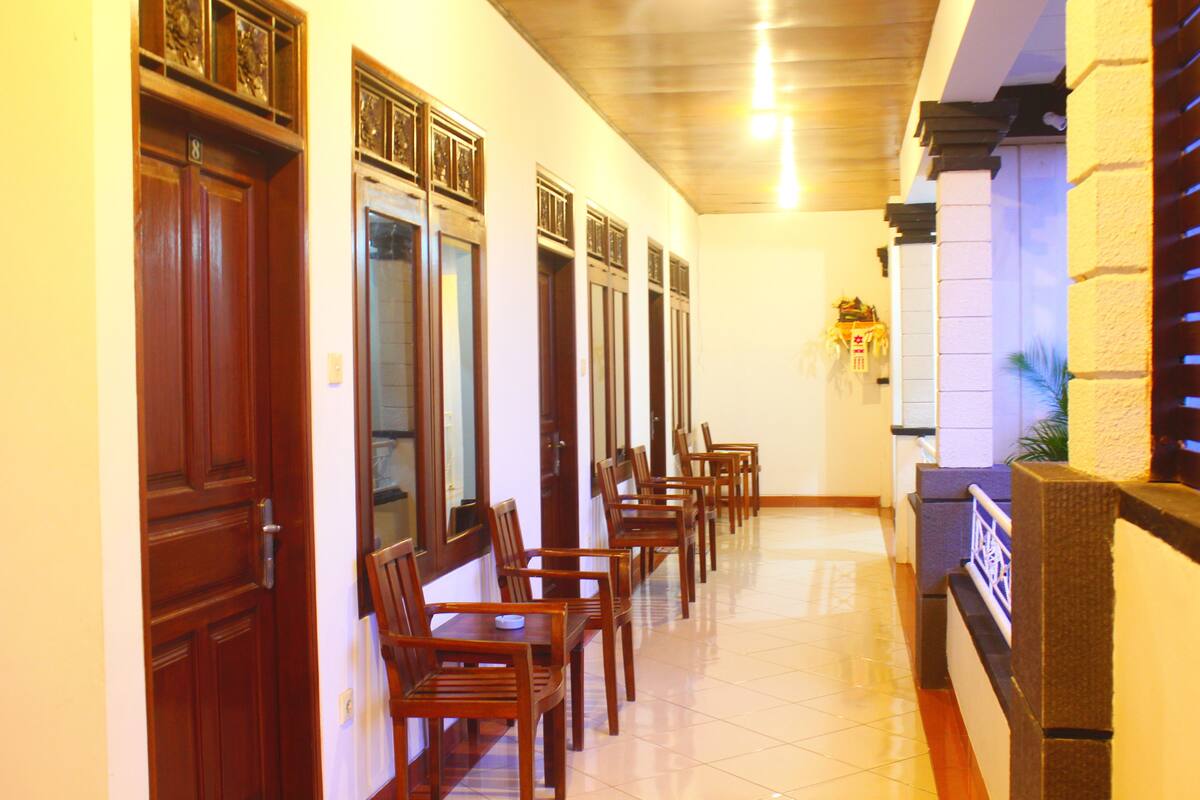 A hallway with wooden doors and a row of chairs.