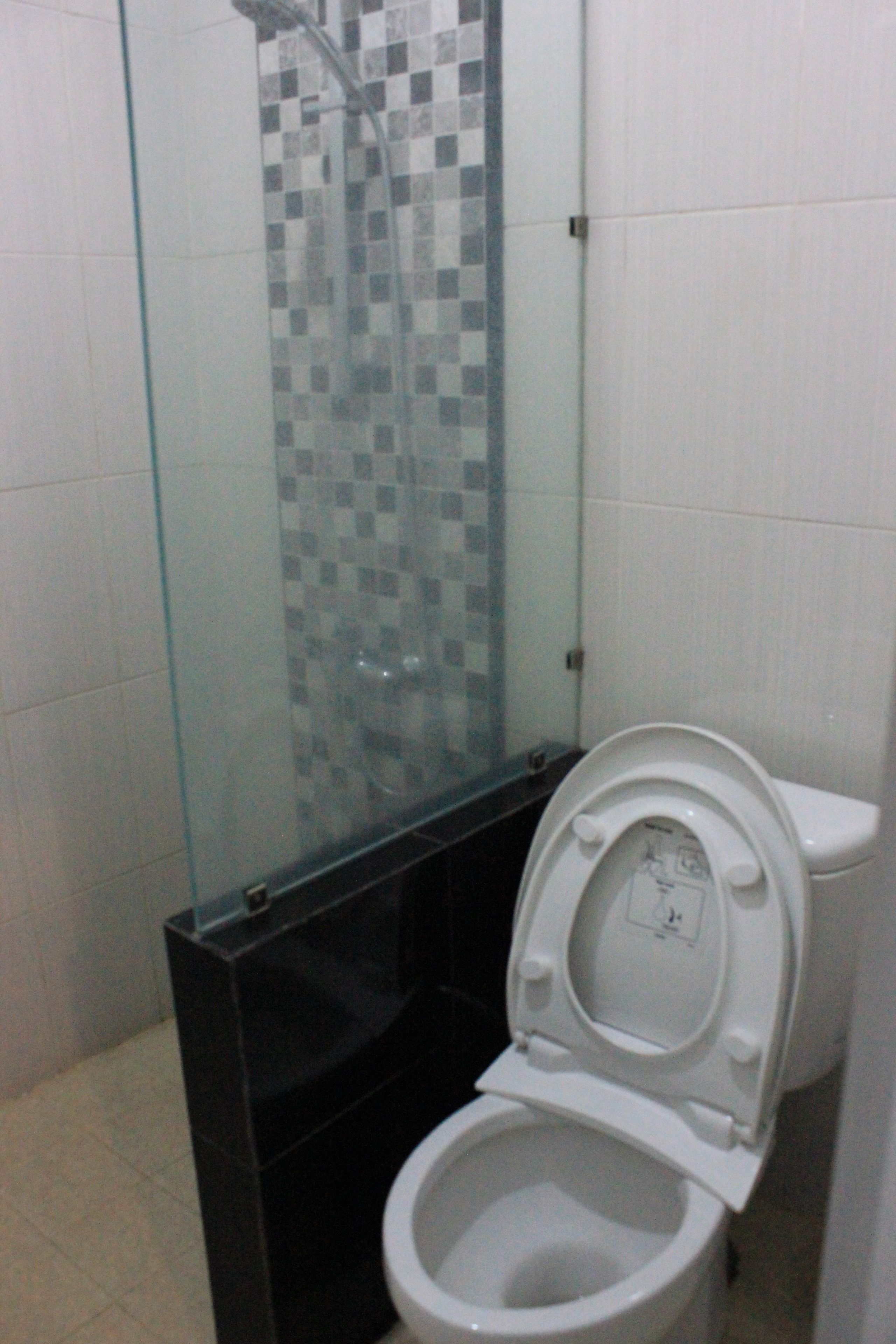 Un baño con cabina de ducha de vidrio, inodoro blanco y lavamanos negro.