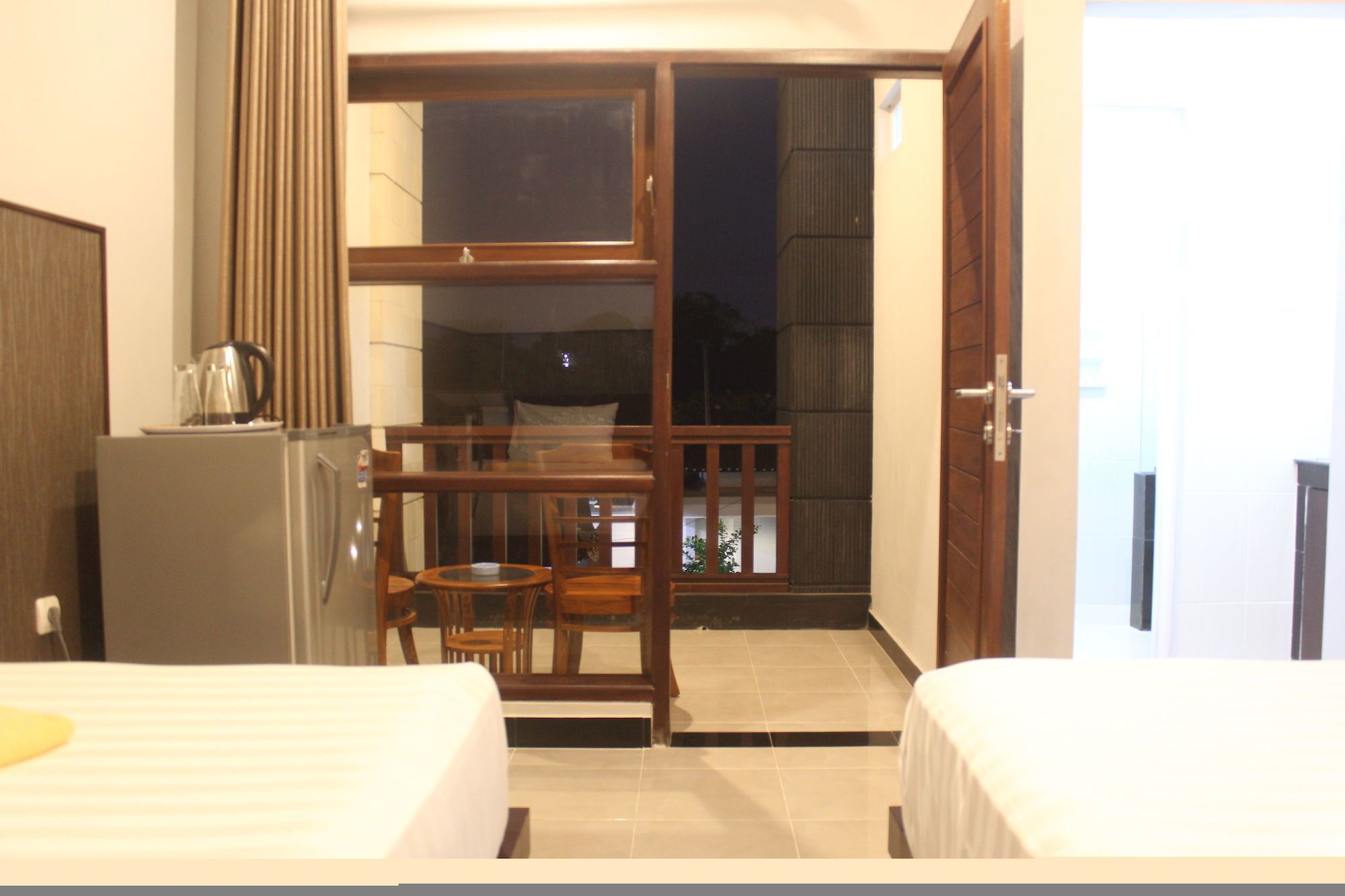 A hotel room with two beds, a kitchenette, and a balcony with a view.