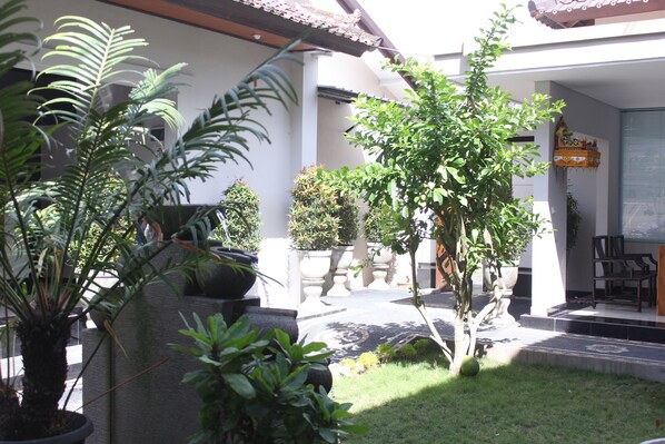 A courtyard with potted plants, a small tree, and a tiled floor. - New Asta Graha Homestay (Kedonganan)