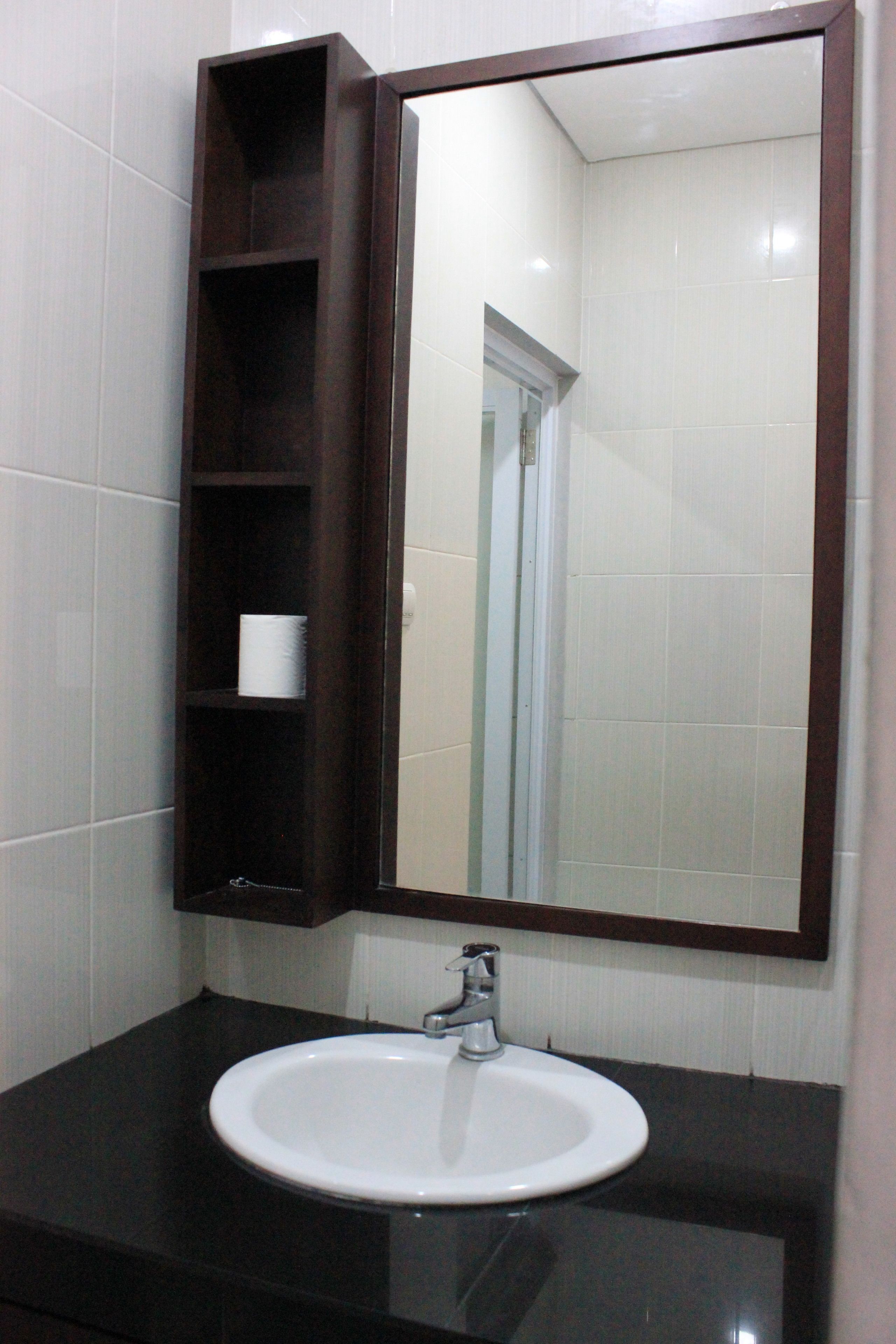 A bathroom with a white sink, dark countertop, and a mirror above it.