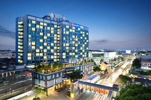 Un hotel moderno con facciata in vetro, diversi piani e un giardino sul tetto.