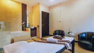 A hotel room with two beds, a bathroom, a small table with a chair, and a telephone.