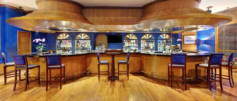 Una zona de bar con techo de madera curvada, taburetes y suelo de madera pulida.