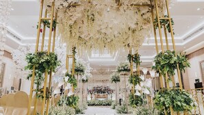 Un salón imponente con un arco floral, sillas elegantes y un arreglo floral central.