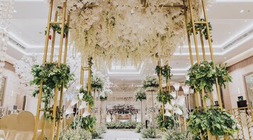 A grand hall with a floral archway, elegant chairs, and a central floral arrangement.