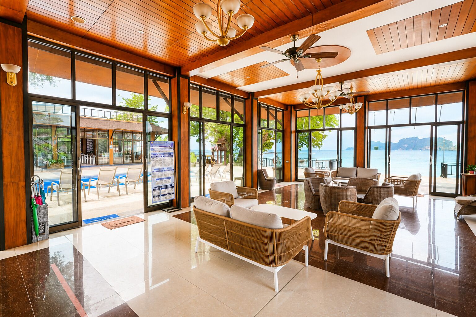A spacious lobby with a pool view, wicker furniture, and a ceiling fan.