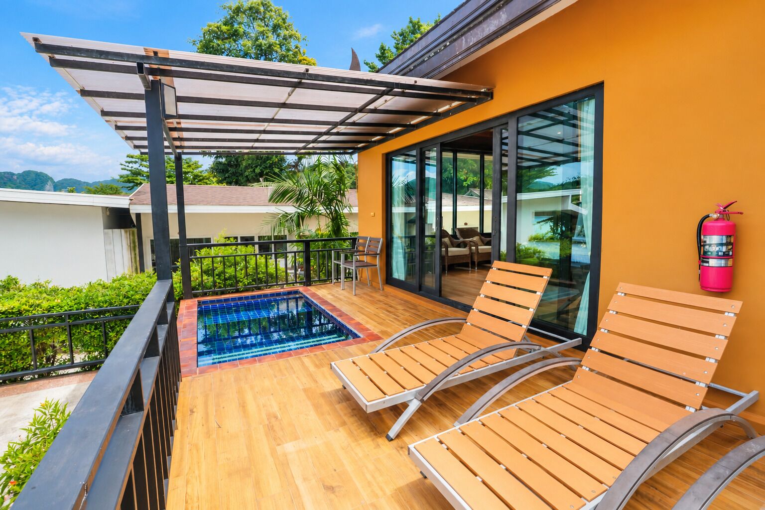 A rooftop terrace with a swimming pool, wooden lounge chairs, and a fire extinguisher.