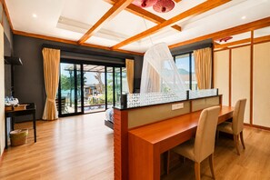 Ein modernes Hotelzimmer mit einem Holztisch, einem Esstisch und einer großen Glasschiebetür, die auf einen Balkon führt.