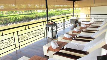 Relax on a sun lounger with a towel and tray, overlooking a serene garden and tranquil water feature.