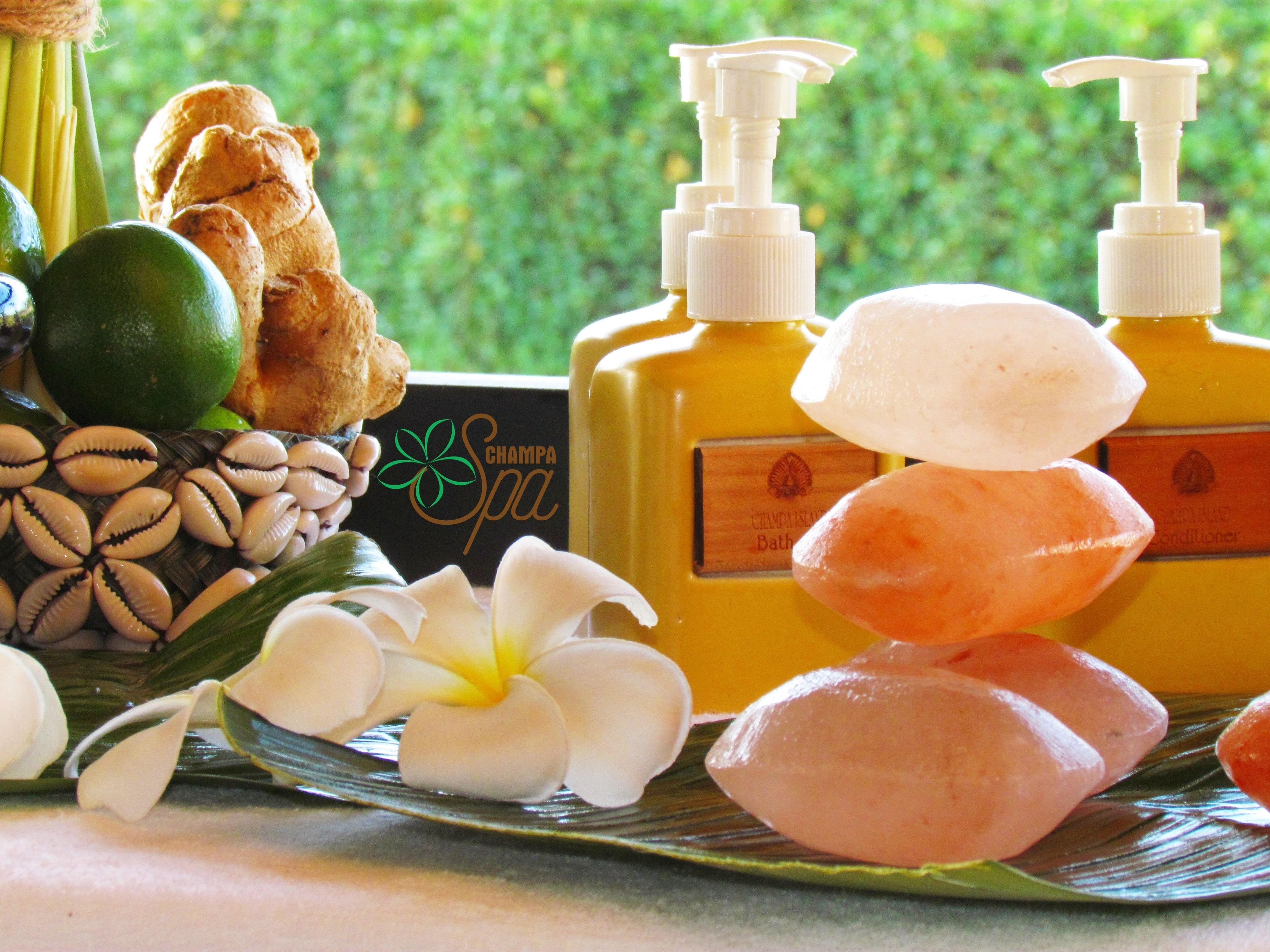 A spa setting with a bottle of bath oil, a bottle of conditioner, and a bowl of snacks.