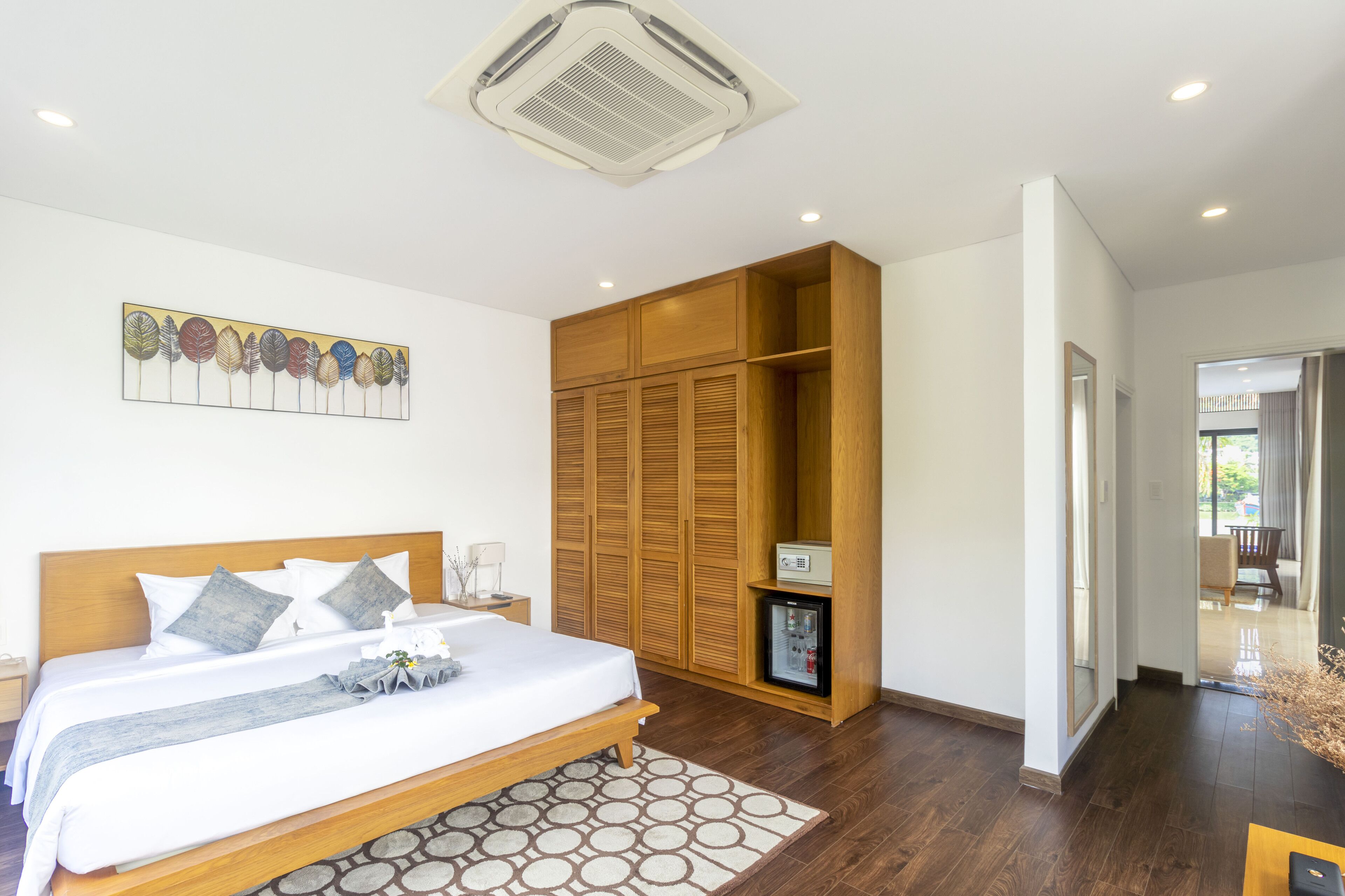 Une chambre à coucher avec un lit, une armoire en bois et un petit réfrigérateur.