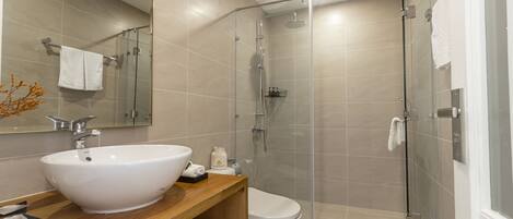 A modern bathroom with a large white sink, a toilet, and a glass-enclosed shower.