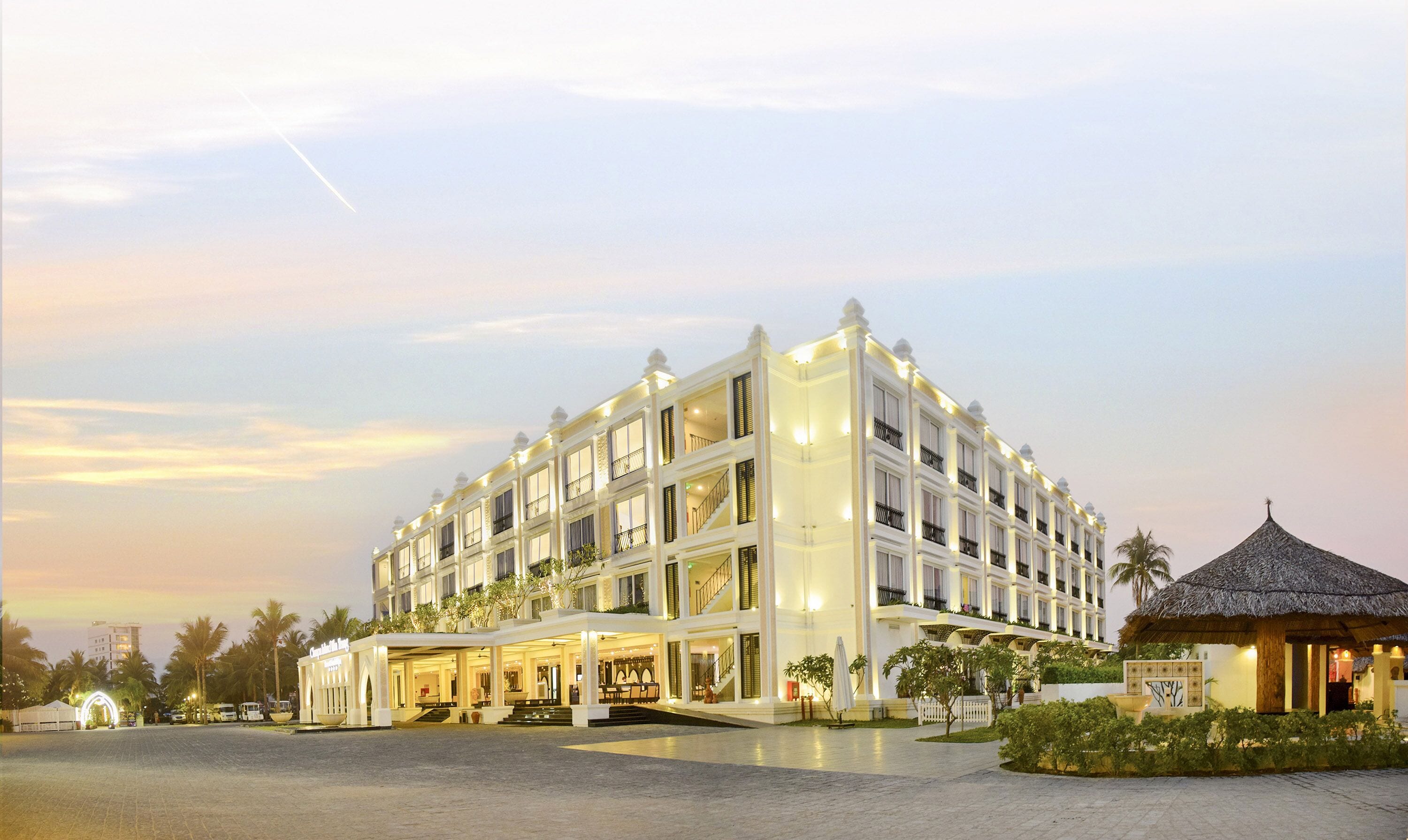 Un hotel de varios pisos con un patio central, balcones y un espacio exterior cubierto.