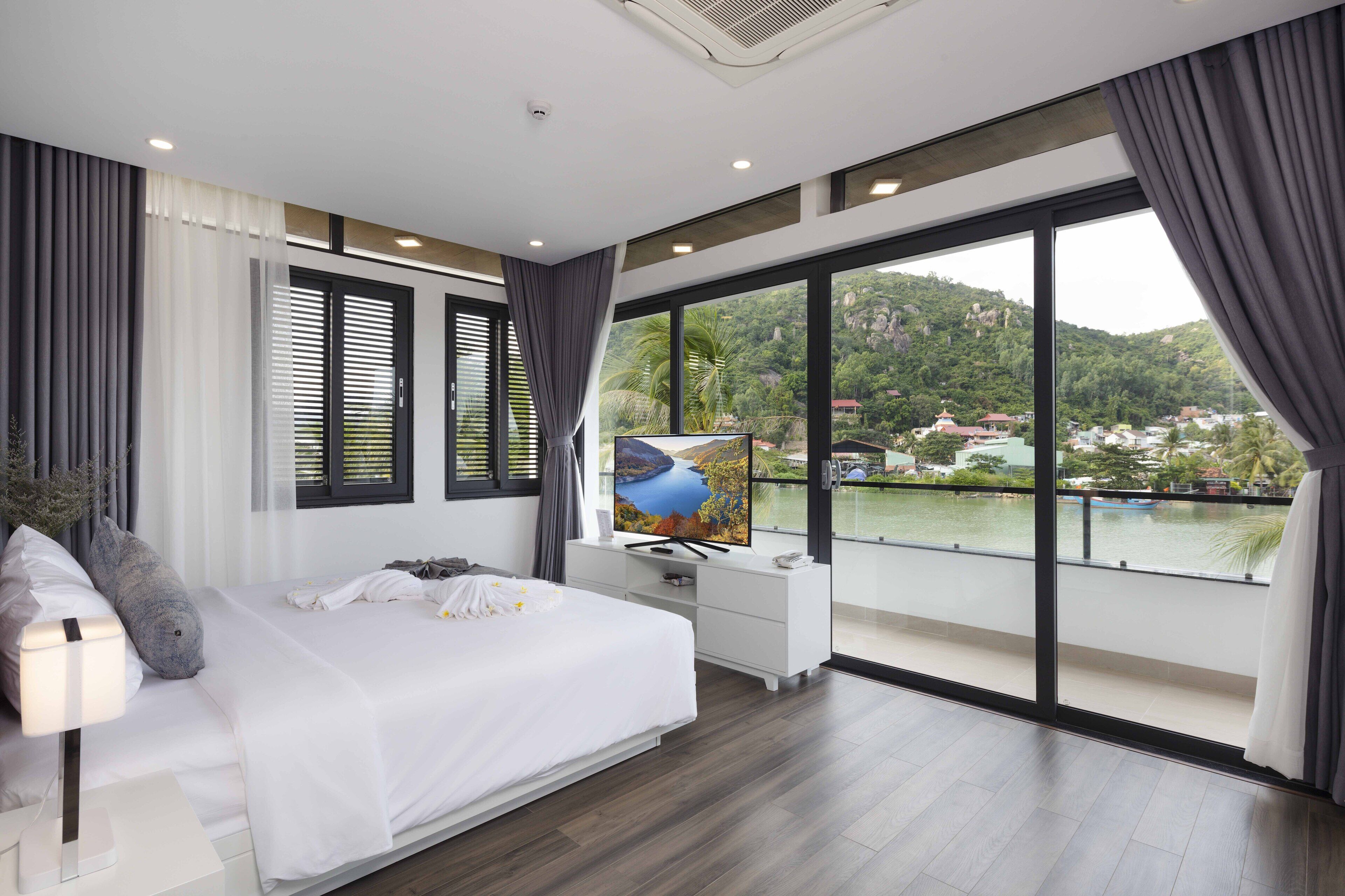 Un dormitorio moderno con una cama grande, un televisor y un balcón con vistas panorámicas.