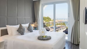 Ein Hotelzimmer mit einem großen Bett, Blick auf die Stadt und einem Balkon mit Geländer.