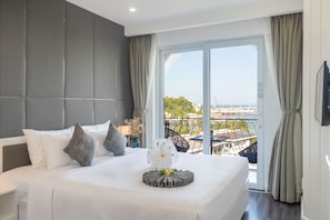 Une chambre d’hôtel avec un grand lit, une vue sur la ville et un balcon doté d’une balustrade.
