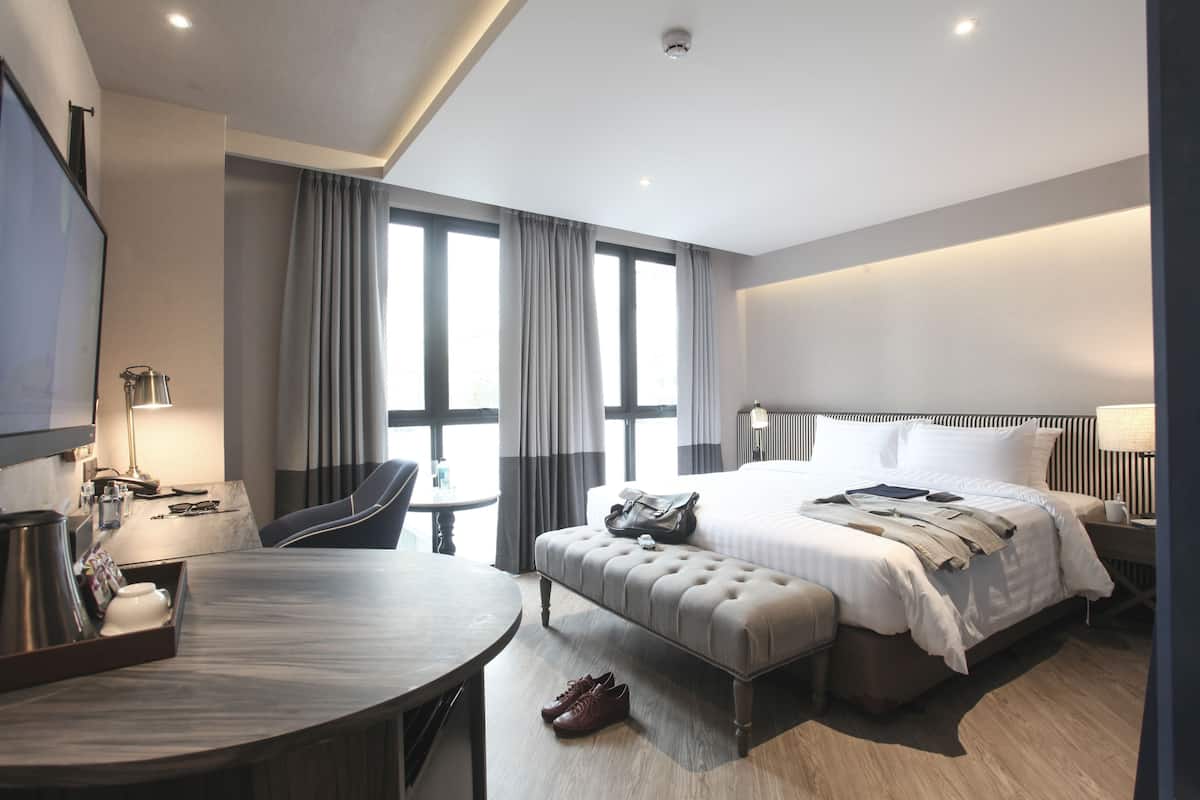 Une chambre d’hôtel moderne dotée d’un grand lit, d’une table de salle à manger ronde, d’un coin salon et d’un téléviseur.