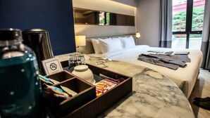 A hotel room with a bed, a tray with snacks, a water bottle, and a no-smoking sign. - Vince Hotel Pratunam (Bangkok)