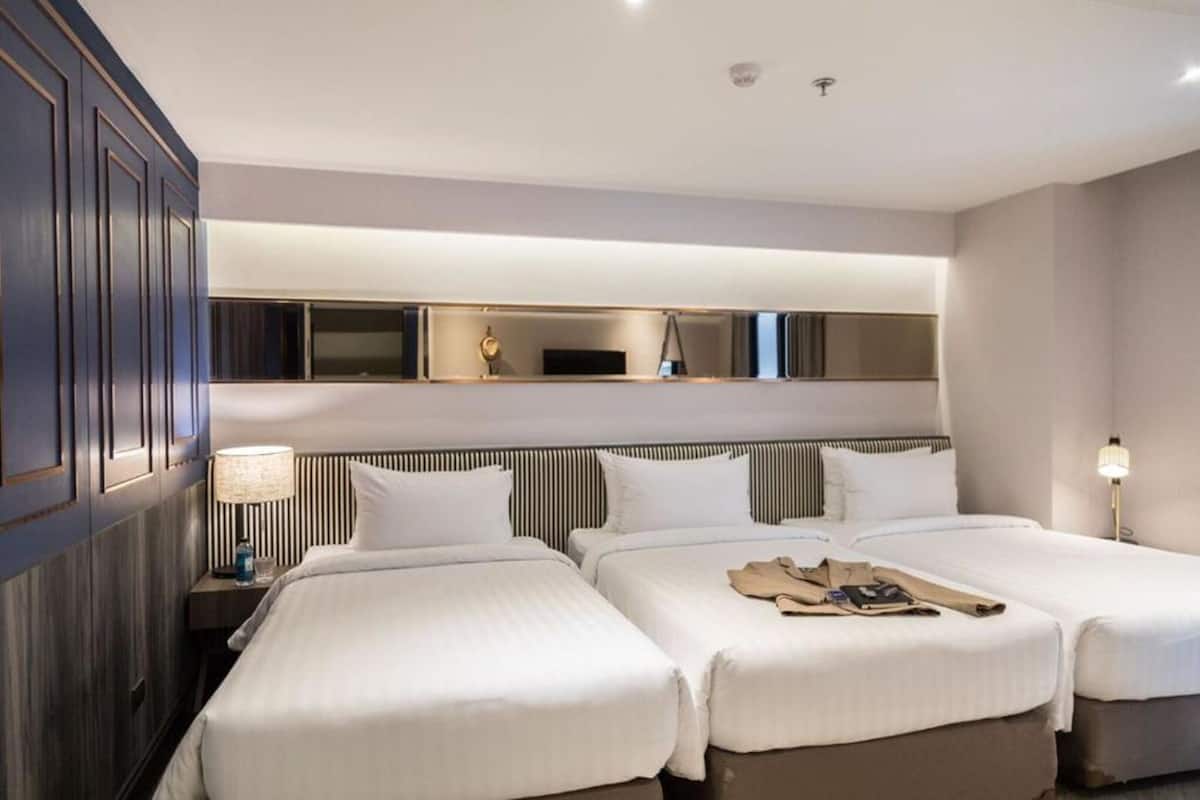 Une chambre d’hôtel avec deux lits, un grand miroir et une télévision.