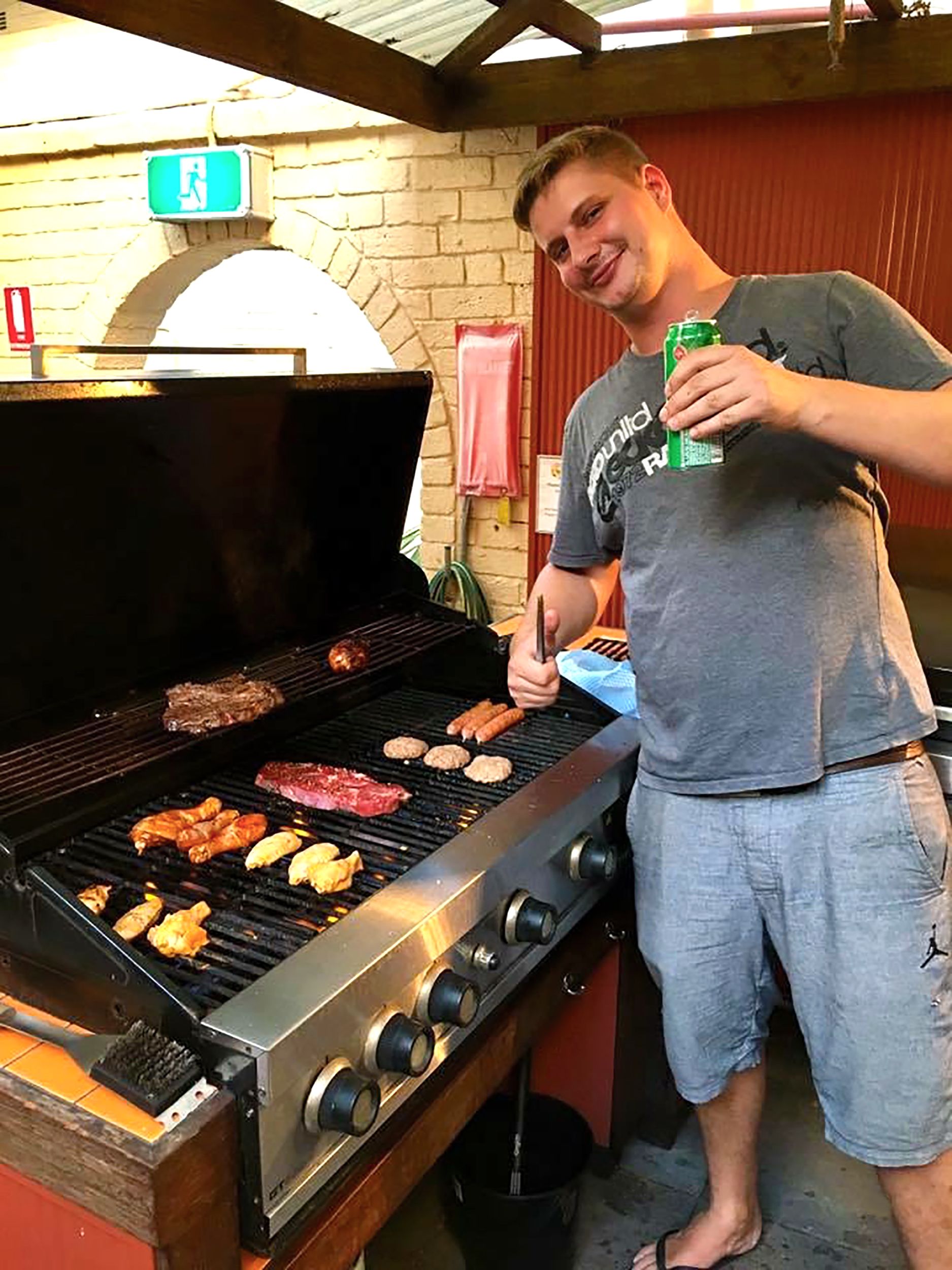 A man grilling various meats on an outdoor grill.