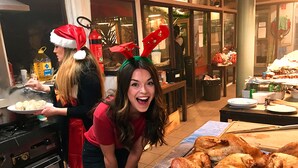 A kitchen area with a stove, a table with a large turkey, and a window with decorations. - Original Backpackers (Potts Point)