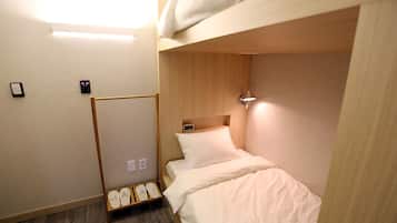 A bunk bed room with a wooden headboard, a bedside table with a lamp, and a shoe rack.