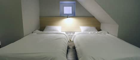 A twin room with two beds, a window, and a wall-mounted light fixture.