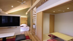 Une chambre d’hôtel moderne équipée d’une télévision à écran plat, d’un lit, d’un bureau et d’un coin repas.