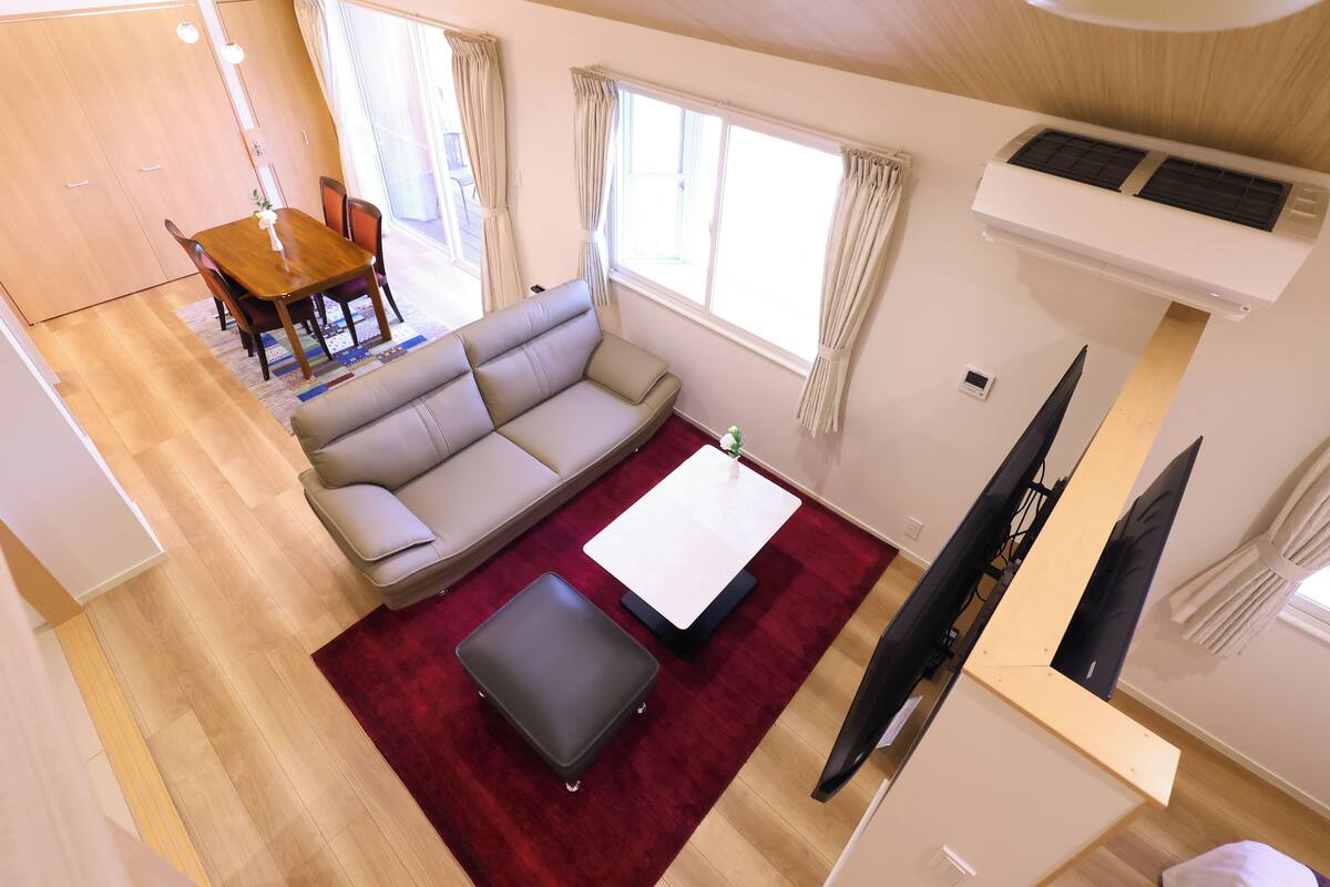 Un espacio habitable compacto con sofá, una mesita, televisor y zona de comedor con sillas y mesa.