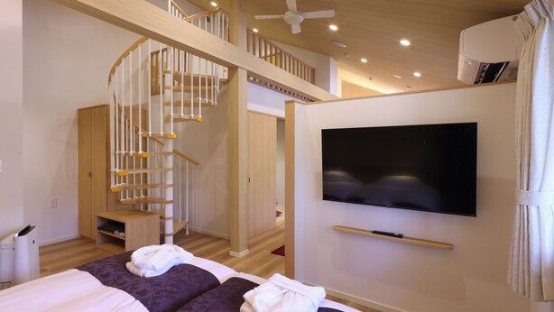 Une chambre d’hôtel avec deux lits, une télévision, un escalier et un ventilateur de plafond.