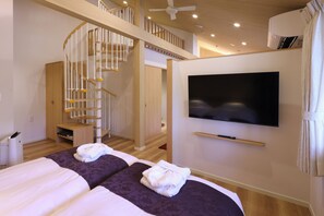 Une chambre d’hôtel avec deux lits, une télévision, un escalier et un ventilateur de plafond.
