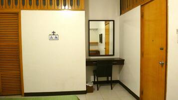 A hotel room with a bed, a desk, a mirror, and a wardrobe.