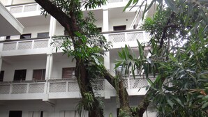 A multi-story building with balconies, surrounded by lush greenery and potted plants. - Pension Natividad (Manila)