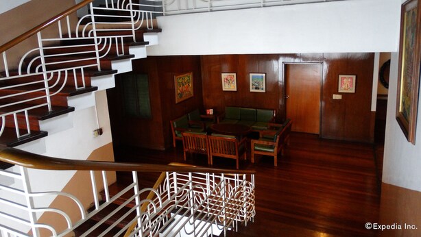 A staircase with ornate white railings and wooden steps leading to a lower level. - Pension Natividad (Manila)